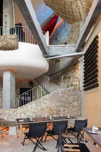 Stone building with a staircase leading to another level, featuring a blend of indoor and outdoor spaces with rustic stone walls and flooring, and seating areas for guests