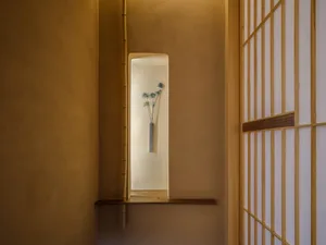 A calm and serene hallway with a concrete wall, two vases with flowers, and a minimalist aesthetic