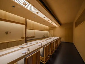 Empty restaurant with wooden floors and walls, featuring dining tables and chairs, clean and inviting atmosphere
