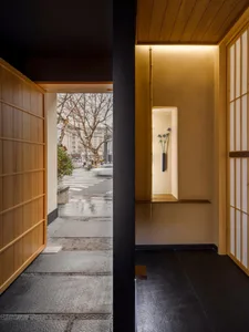 Black and white hallway with potted plants and a vase, leading to a modern living area