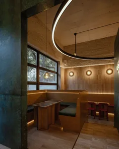 Warm and inviting restaurant interior with wooden walls and floors, featuring dining tables, chairs, and benches