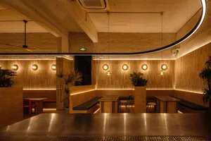 Warm and inviting restaurant interior with wooden walls, tables, and chairs, surrounded by potted plants