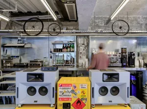 工業風廚房，配有兩個喇叭、酒瓶與杯子，營造出實用工作區與社交聚會空間