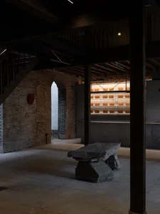 A modern interior space with a stone wall, a large stone table, and books, featuring a warm and inviting ambiance