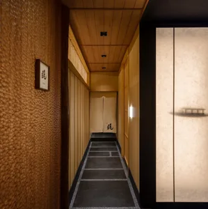 A calm and serene Asian-style hallway with wooden walls and floors, featuring a black door frame and two doors leading to other rooms