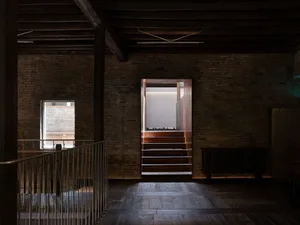 A rustic living and dining space with brick walls, wooden floors, and a large window providing natural light