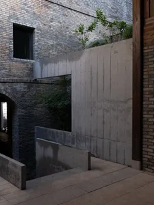 A modern building with a concrete staircase leading to a lower level, well-lit by natural light through windows or skylights