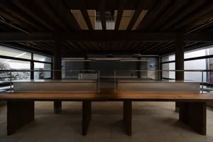 Spacious dining room with a large wooden table and chairs, well-lit with high ceilings and modern design elements