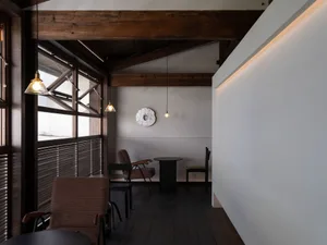 Warm and inviting living space with wooden floors and walls, featuring multiple chairs and dining tables, with a focus on comfort and functionality