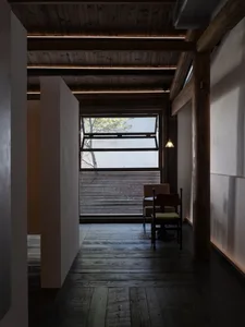 Cozy living space with wooden floors and walls, featuring a dining table, chairs, and a couch