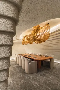 A dining area in a restaurant with a long wooden table set for guests, surrounded by chairs and bottles of beverages