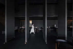 A quiet and inviting restaurant with a black and white theme, featuring dining tables and chairs in a spacious hallway
