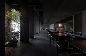A modern restaurant with a large dining area featuring multiple tables and chairs, creating a calm and inviting atmosphere