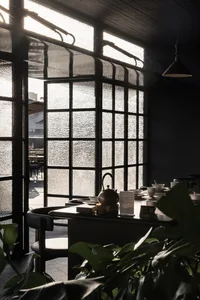 A dimly lit restaurant dining area with a wooden table and chairs, decorated with vases and bowls, creating a cozy ambiance