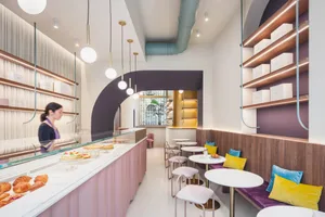 Inviting restaurant interior with wooden accents, multiple tables, and a counter displaying desserts