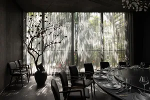 A well-lit dining area with a round table set for guests, surrounded by chairs and decorative vases, creating a warm and inviting atmosphere