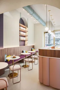 A restaurant interior with wooden floors and walls, featuring dining tables, chairs, couches, and a warm atmosphere