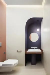 A modern bathroom with a white toilet, wooden countertop, and a circular mirror above the sink, creating a clean and well-organized space with a focus on functionality and aesthetics