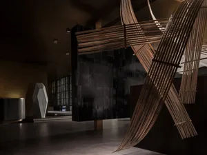 A wooden sculpture of a cross in a dimly lit room, creating a moody atmosphere