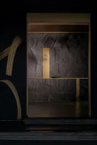 A serene Asian-style interior space with a stone wall, wooden countertop, and two doors, featuring a mix of stone and wood elements