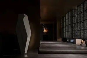 Elegant hallway with a stone wall, marble floor, vases, and a potted plant, creating a sophisticated atmosphere