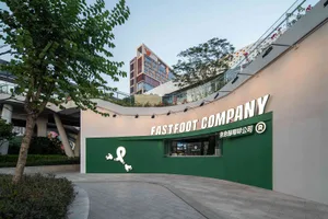 一座擁有玻璃立面的現代辦公大樓，綠色招牌寫著 Fastfoot Company，專業氛圍濃厚