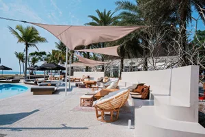 A resort patio with multiple chairs and couches under large umbrellas, creating a shaded and inviting seating area