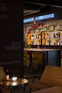 A casual bar area with a counter, bottles of alcohol, wine glasses, and a graffiti wall in the background
