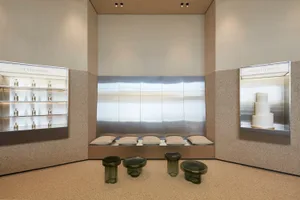 A modern showroom with various seating options, including couches, benches, and chairs, in a clean and contemporary space with white and silver tones