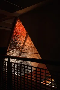 A modern glass triangle building with a red interior, featuring a unique design and contemporary architectural style