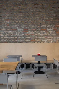 Modern restaurant interior with wooden tables, brick walls, and comfortable seating for guests