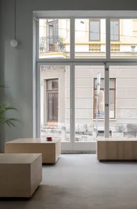Interior view of a cozy living space with wooden tables, a red cup, and natural light from large windows