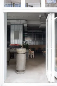 休閒餐廳內部，一隻狗狗置身中央，周圍環繞著椅子與桌椅，左側擺放盆栽，營造輕鬆氛圍