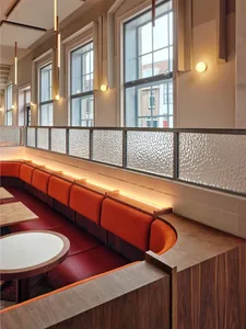 rows of wooden benches and dining tables in a restaurant or cafeteria with natural light from windows
