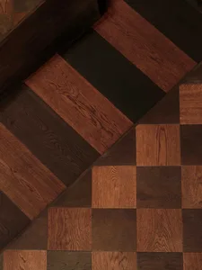A wooden staircase with a checkered pattern on its steps, set against a neutral background, with a calm and inviting atmosphere