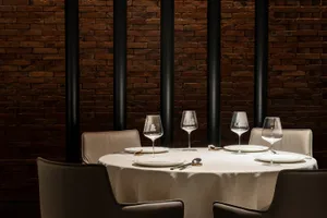 A round dining table set with white linen and wine glasses, surrounded by chairs in a sophisticated and inviting atmosphere