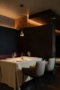 Dining area with a long wooden table and chairs, set with wine glasses and bottles, creating a sophisticated atmosphere for meals and socializing