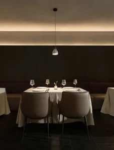 A formal dining area with a large table and chairs, wine glasses, and neatly arranged utensils, set in a sophisticated and inviting atmosphere