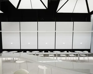 Empty modern restaurant interior with white walls, dining tables, and chairs, giving off a clean and minimalist atmosphere