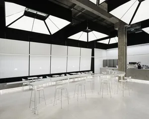 Bright and inviting commercial space with multiple dining tables, chairs, and cups, set in a high-ceilinged room