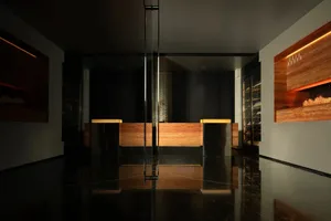 Darkened office space with a reception desk, two chairs, and a pole, featuring a modern and functional style