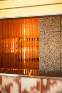 A modern space with an orange glass wall reflecting the surroundings and a brown brick wall in the background