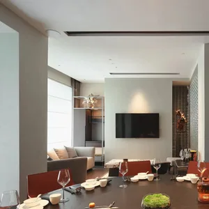 Contemporary living space with a flat screen TV, chairs, and dining table, surrounded by wine glasses, in a modern building