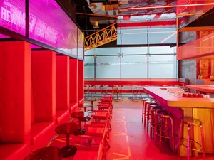 Inviting bar area with a long red counter and stools, surrounded by chairs and a comfortable atmosphere
