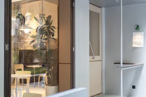 A well-lit room with a large window, chairs, and potted plants, creating an inviting atmosphere for relaxation