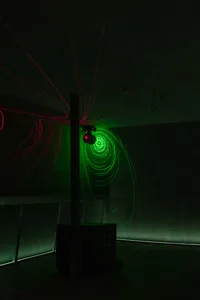 A modern room with a green neon light creating a spiral effect on the wall, featuring two large speakers and a futuristic atmosphere