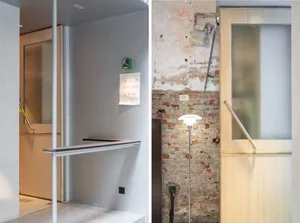 A rustic bathroom with brick walls, a stairwell, and two sinks, one near a brick wall, with signs and a simple design