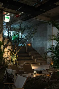 Cozy living space with a staircase, dining table, couch, and potted plant, surrounded by warm and inviting atmosphere