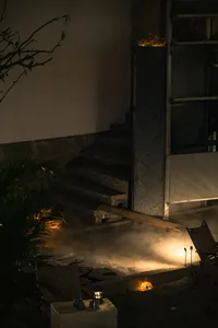 A dimly lit interior space with a concrete staircase, a chair, and a doorway