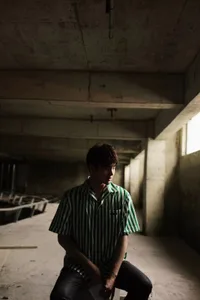 A man stands in a room with a concrete wall and cement floor, giving it an industrial feel